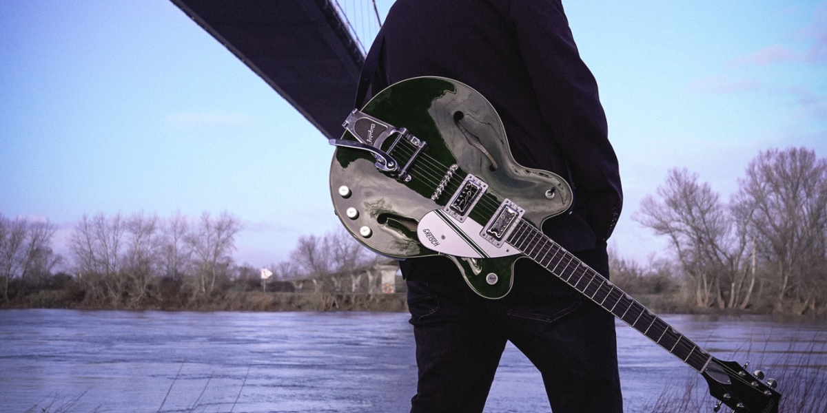 Mann mit Gitarre am Fluss